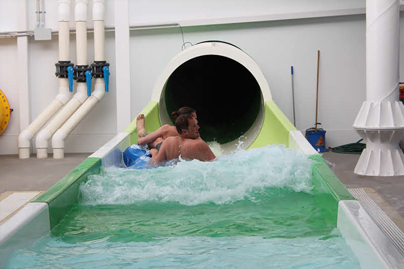 Two people emerging at the end of the tumbler raft slide
