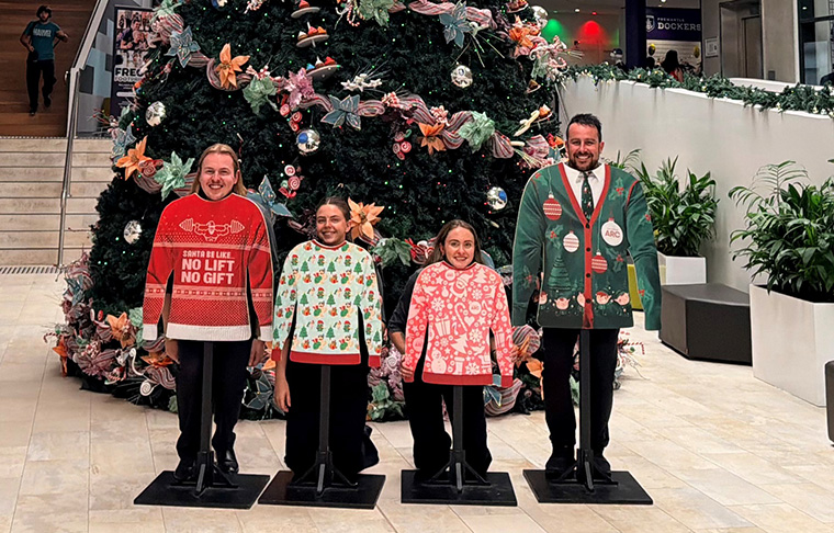Four staff members standing in front of a Christmas tree