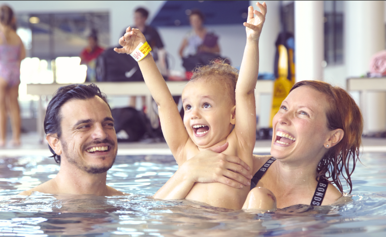 Mum and dad swimming with their son in the water.