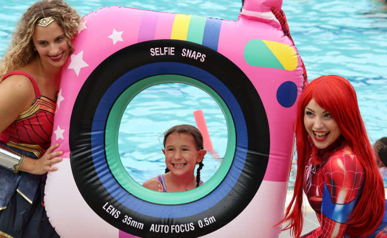 Two superhero's smiling with a young girl.