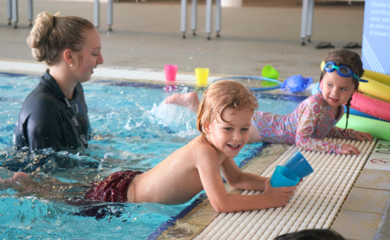 Children learning to swim with their instructor.