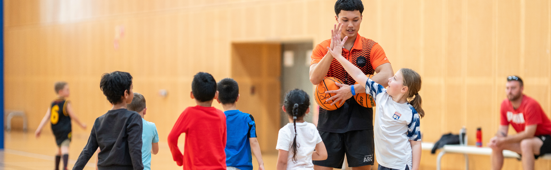 Kids playing sports with the help of a coach.
