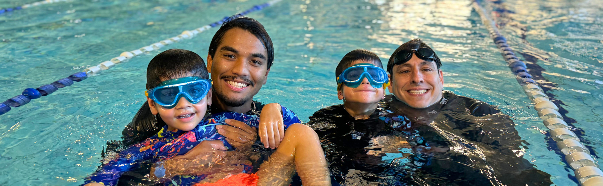 Instructors with two swimmers in the water.