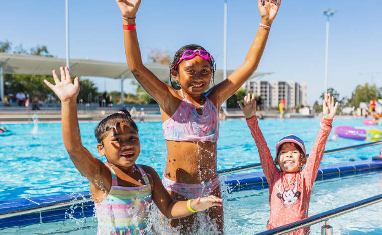 Kids jumping out of the water, smiling.