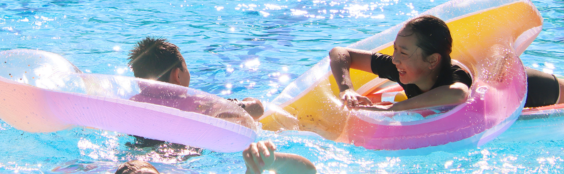 two kids playing with inflatable toys in the pool