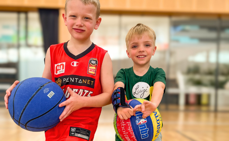 Kids playing basketball, smiling at the camera