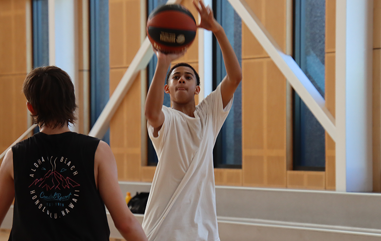 A young boy aiming a basketball at a hoop
