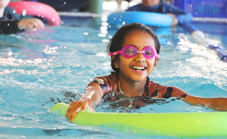 Girl swimming in the water with a noodle.