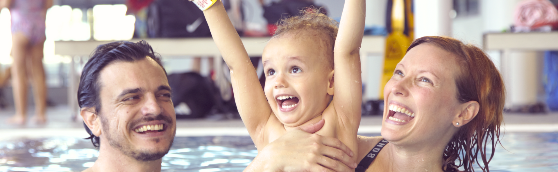 Mum and dad swimming with their son in the water.