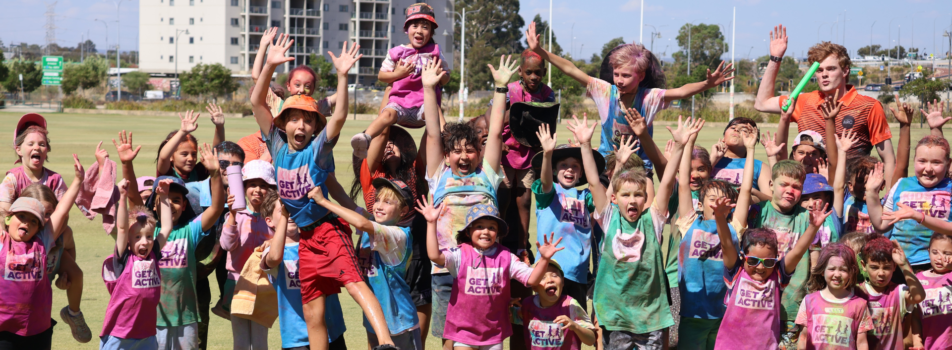 Photo of Kids jumping up in a group, smiling and laughing. 