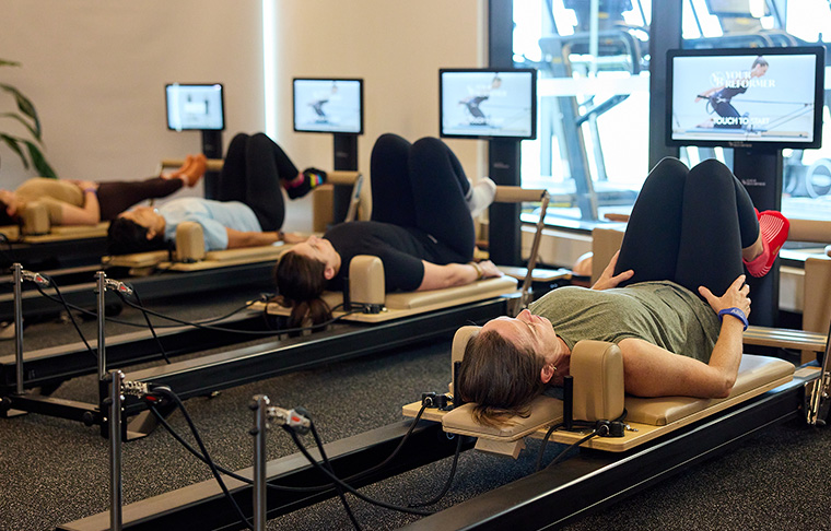 Four women working out on reformer pilates machines