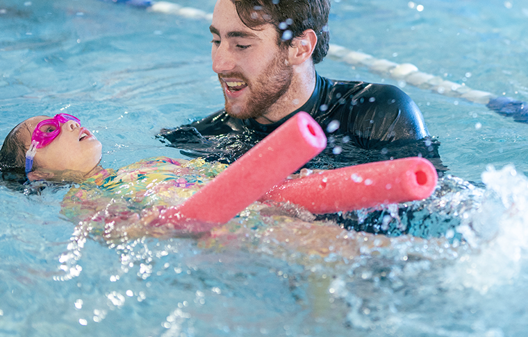 Swim instructor helps student float