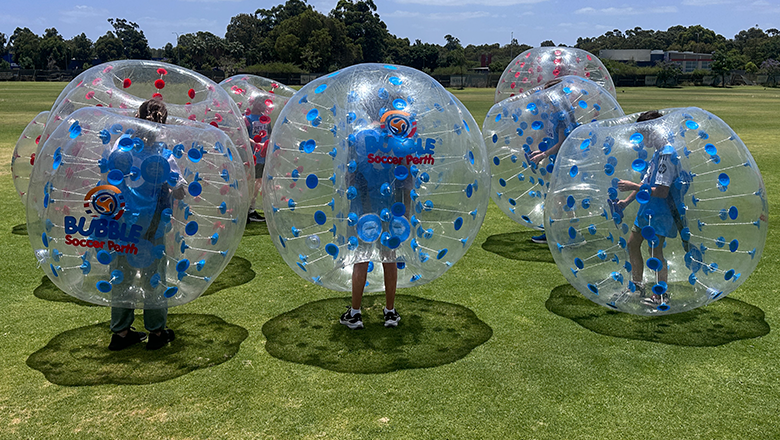 Kids playing bubble soccer on the oval